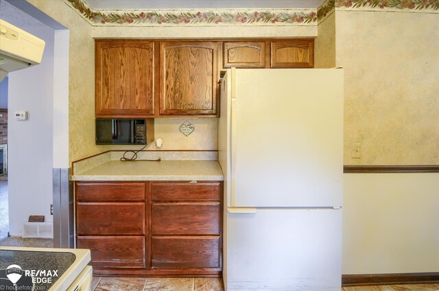 500 Granger Rd, Ortonville, MI 48462 - kitchen with freestanding refrigerator, black microwave, light countertops, and brown cabinets