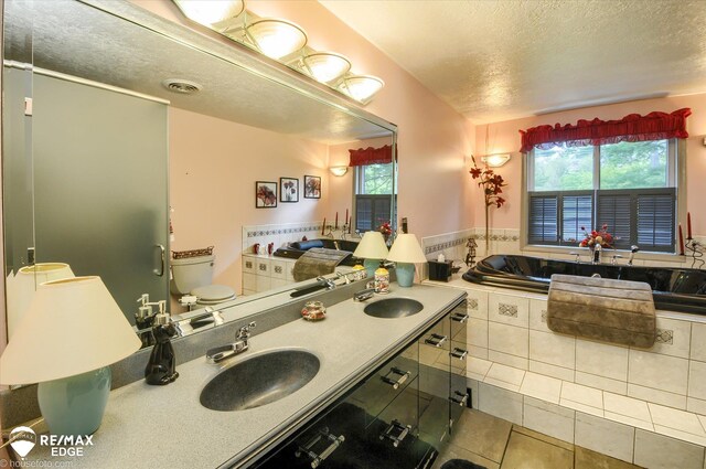 500 Granger Rd, Ortonville, MI 48462 - bathroom with a textured ceiling, plenty of natural light, tile patterned floors, toilet, and a relaxing tiled tub