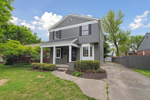 view of front of house featuring a porch, driveway, brick siding, and a gate