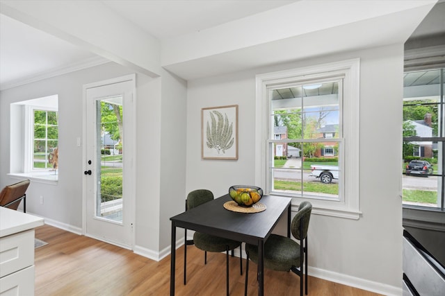 dining space with light wood-style flooring, baseboards, plenty of natural light, and ornamental molding