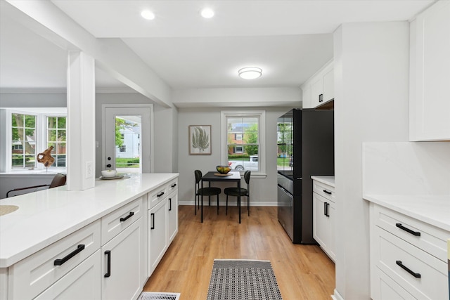 kitchen featuring freestanding refrigerator, white cabinets, light wood finished floors, plenty of natural light, and recessed lighting
