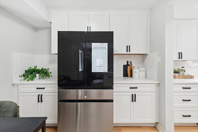 kitchen featuring smart refrigerator, tasteful backsplash, white cabinets, light countertops, and light wood finished floors