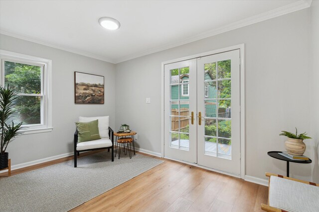 living area with french doors, ornamental molding, light wood-style floors, and healthy amount of natural light