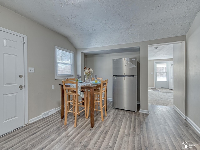 19106 Sylvia Ave, Romulus, MI 48174 - dining space with light wood-type flooring, a textured ceiling, lofted ceiling, and baseboards