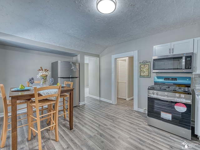 19106 Sylvia Ave, Romulus, MI 48174 - dining room featuring a textured ceiling, vaulted ceiling, light wood-style floors, and baseboards