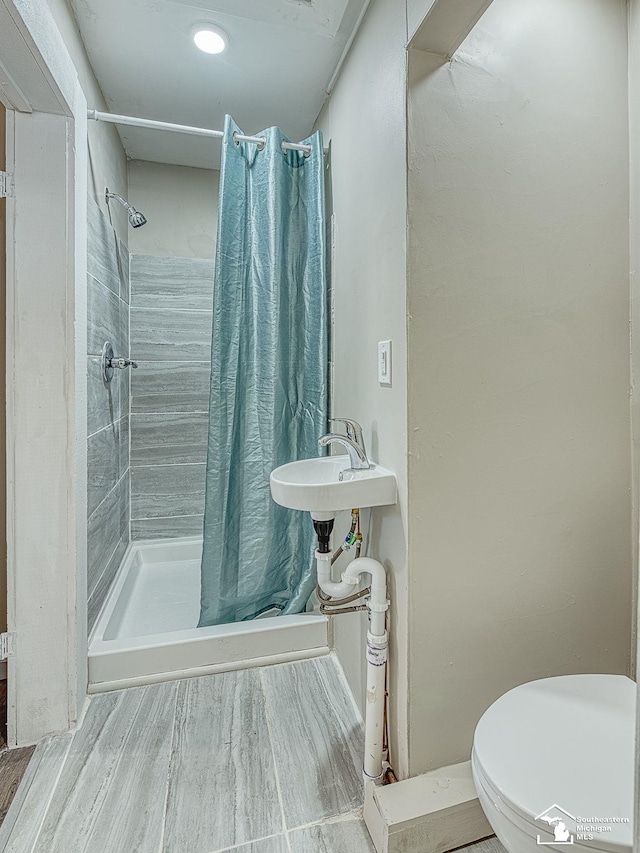 19106 Sylvia Ave, Romulus, MI 48174 - bathroom with a stall shower, toilet, a sink, and wood finished floors
