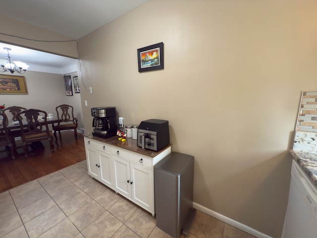 475 N Eton St Unit C7, Birmingham, MI 48009 - kitchen with light tile patterned floors, a chandelier, white cabinets, dark countertops, and baseboards