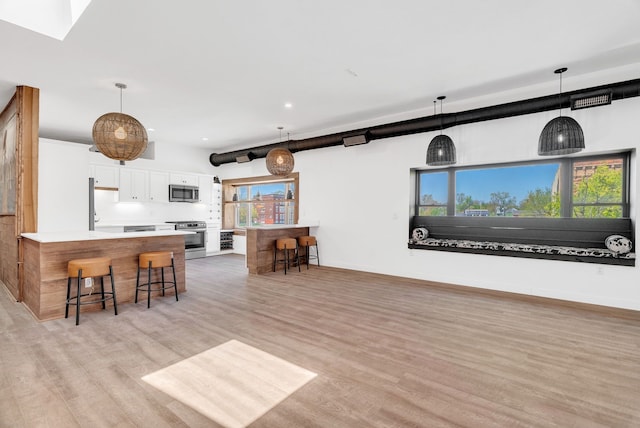 436 E Milwaukee St Unit 8, Detroit, MI 48202 - kitchen with stainless steel appliances, a kitchen breakfast bar, white cabinetry, light wood-type flooring, and recessed lighting