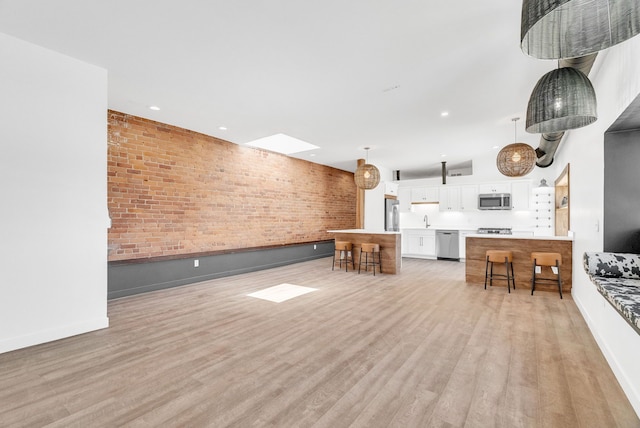 436 E Milwaukee St Unit 8, Detroit, MI 48202 - living area with light wood-style floors, baseboards, recessed lighting, brick wall, and a skylight