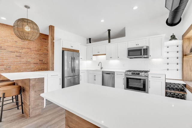 436 E Milwaukee St Unit 8, Detroit, MI 48202 - kitchen featuring stainless steel appliances, a sink, brick wall, a peninsula, and light wood finished floors