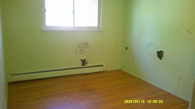 8240 Hampton Rd, Grosse Ile, MI 48138 - unfurnished room featuring a baseboard heating unit, wood finished floors, and baseboards