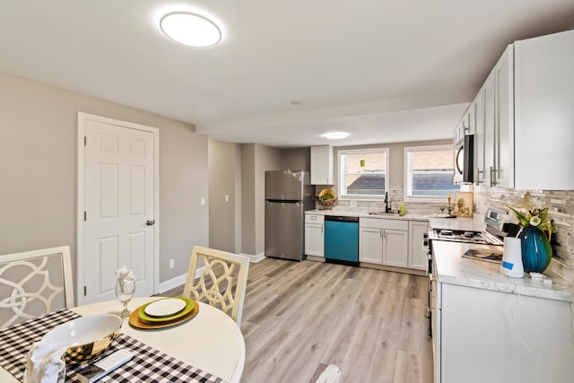 532 Chestnut St, Wyandotte, MI 48192 - kitchen with stainless steel appliances, a sink, decorative backsplash, light countertops, and light wood finished floors