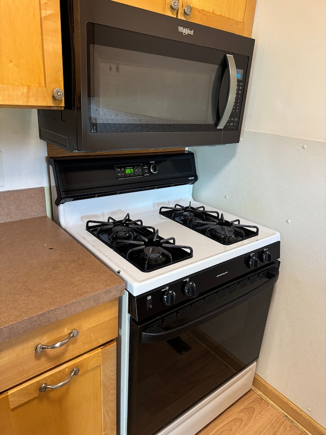 35221 Tall Oaks Dr, Sterling Heights, MI 48312 - kitchen with gas stove, black microwave, and brown cabinets