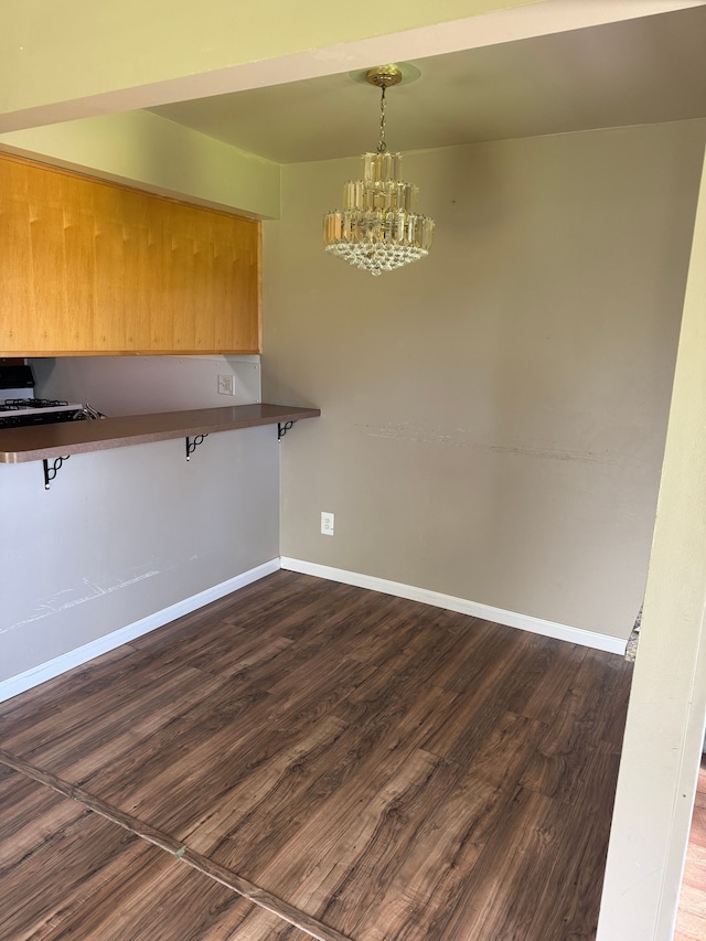 35221 Tall Oaks Dr, Sterling Heights, MI 48312 - kitchen with a chandelier, dark wood-type flooring, dark countertops, baseboards, and a breakfast bar
