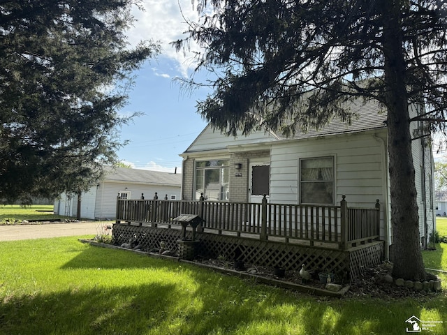 4971 Elm St, Newport, MI 48166 - view of front facade featuring a wooden deck, a front yard, an attached garage, and driveway