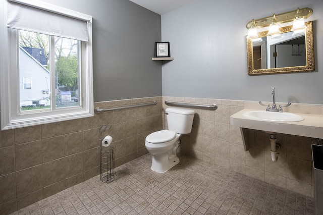 1309 Division St, Port Huron, MI 48060 - bathroom with a sink, toilet, wainscoting, tile walls, and tile patterned flooring