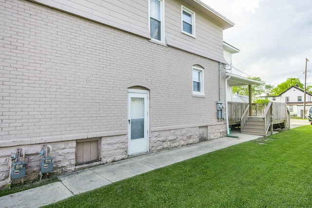 1309 Division St, Port Huron, MI 48060 - view of side of property with brick siding, a lawn, and a deck
