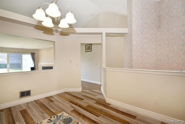 34214 Birchway Cir, Sterling Heights, MI 48312 - spare room with a chandelier, wood finished floors, baseboards, a fireplace, and lofted ceiling