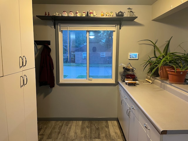 kitchen with wood finished floors, white cabinetry, light countertops, and baseboards