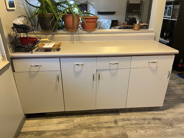 kitchen with wood finished floors, white cabinetry, and light countertops