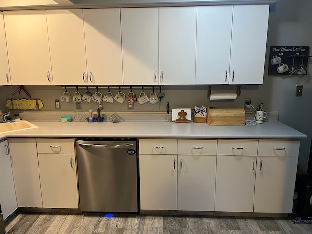 kitchen featuring stainless steel dishwasher, light countertops, light wood-style flooring, white cabinets, and a sink