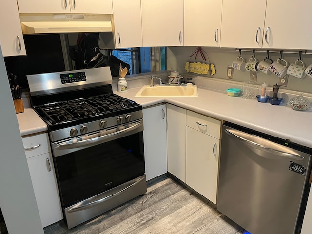 kitchen with appliances with stainless steel finishes, under cabinet range hood, light countertops, and light wood-type flooring