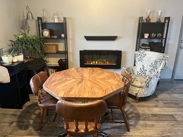 dining space with wood finished floors and a glass covered fireplace