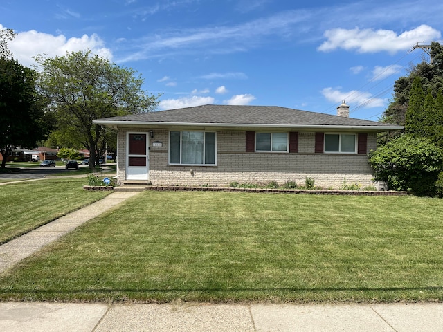 view of front of house featuring brick siding, a front yard, and a chimney