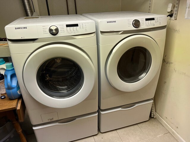 laundry area with washing machine and clothes dryer and light tile patterned floors