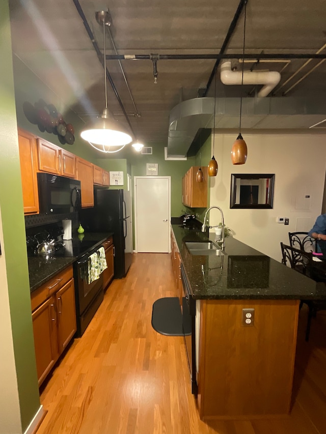66 Winder St Unit 325, Detroit, MI 48201 - kitchen with black appliances, light wood finished floors, a sink, dark stone counters, and a peninsula
