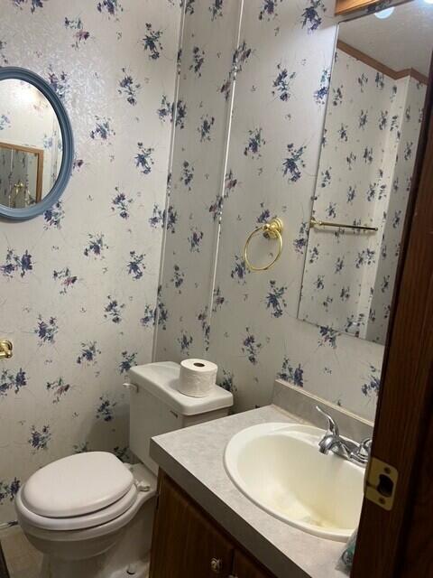 bathroom featuring wallpapered walls, toilet, crown molding, and vanity