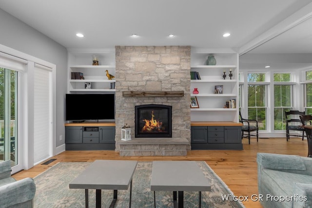 631 Greenslate Dr SE, Ada, MI 49301 - living room with a stone fireplace, light wood-style floors, built in features, and recessed lighting
