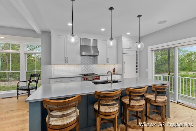 631 Greenslate Dr SE, Ada, MI 49301 - kitchen featuring wall chimney range hood, a sink, paneled built in refrigerator, tasteful backsplash, and white cabinetry