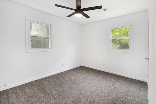 empty room with dark colored carpet, ceiling fan, and baseboards