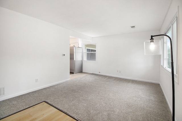 unfurnished room featuring light carpet and baseboards