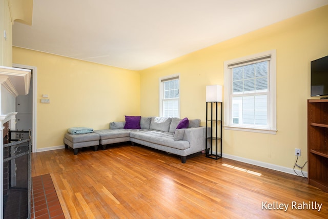living area with light wood finished floors, baseboards, and a fireplace with flush hearth