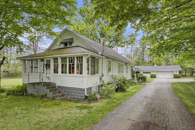 view of front facade featuring an outdoor structure, a chimney, a front yard, and a garage