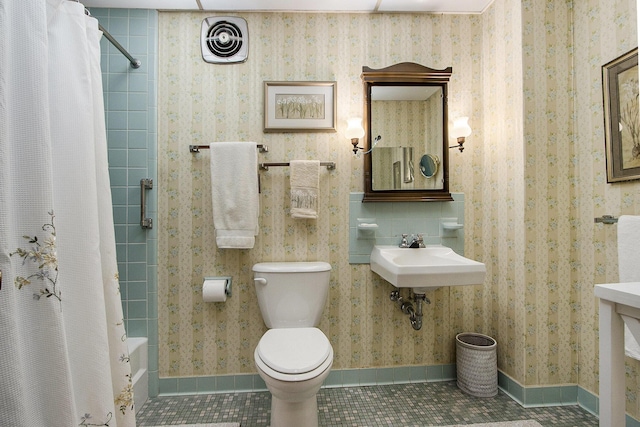 bathroom featuring toilet, a sink, tile patterned flooring, and shower / tub combo