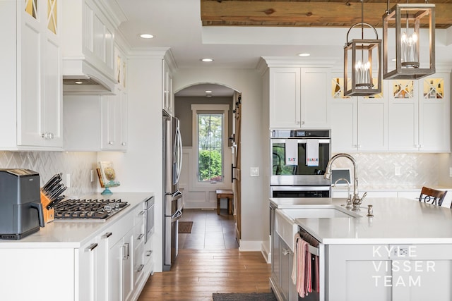 11650 Lally St NE, Lowell, MI 49331 - kitchen with arched walkways, recessed lighting, stainless steel appliances, light countertops, and dark wood-style flooring