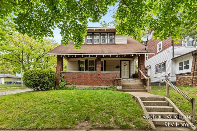 view of front of house featuring brick siding, a front lawn, and covered porch