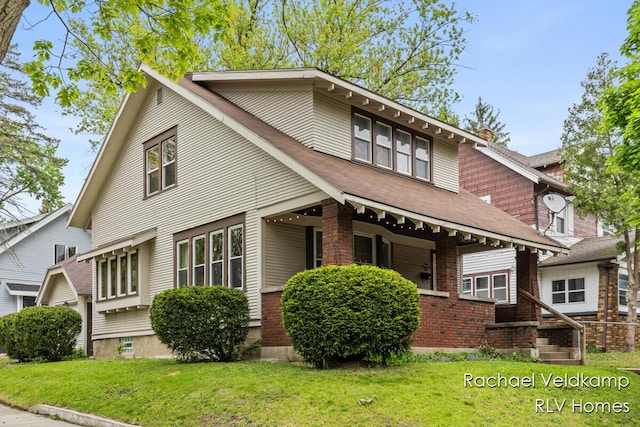 mid-century inspired home with a front yard, covered porch, brick siding, and a chimney