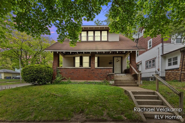 view of front of house featuring a front lawn, brick siding, and covered porch
