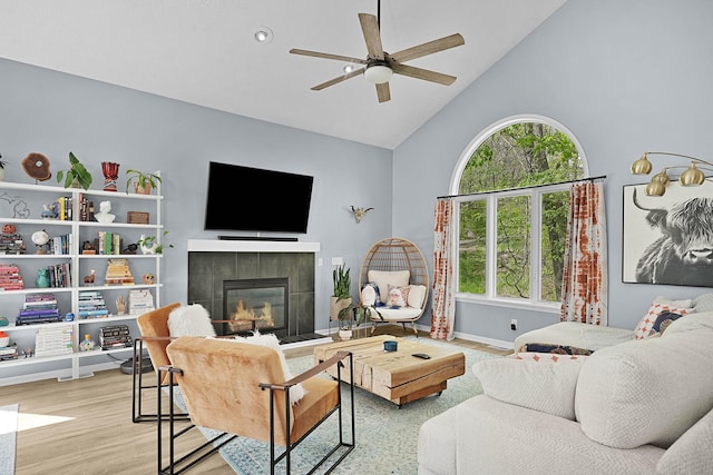 12700 Mcpherson St NE, Lowell, MI 49331 - living room with high vaulted ceiling, a tiled fireplace, a ceiling fan, wood finished floors, and baseboards