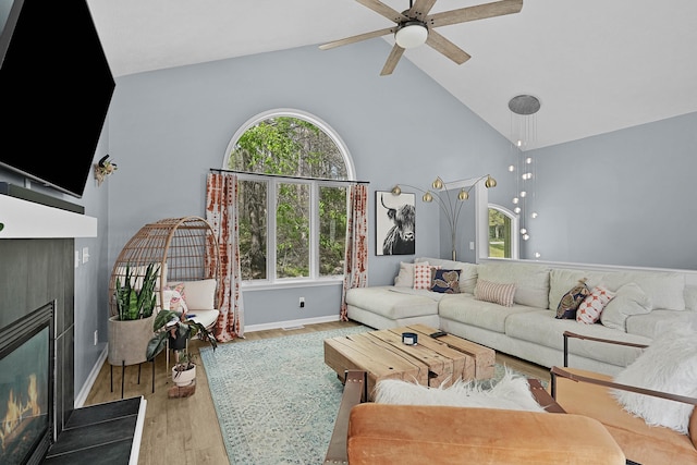 12700 Mcpherson St NE, Lowell, MI 49331 - living room featuring a glass covered fireplace, high vaulted ceiling, wood finished floors, ceiling fan, and baseboards
