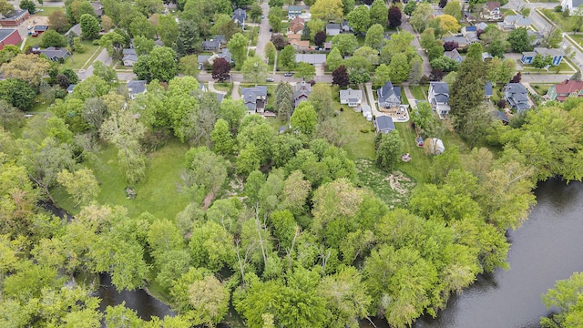 aerial view of property and surrounding area with a large body of water, nearby suburban area, and a tree filled landscape