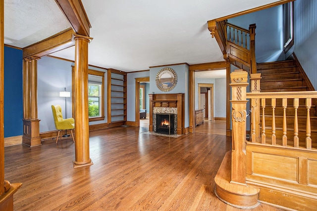 unfurnished living room featuring wood finished floors, baseboards, a fireplace with flush hearth, and crown molding