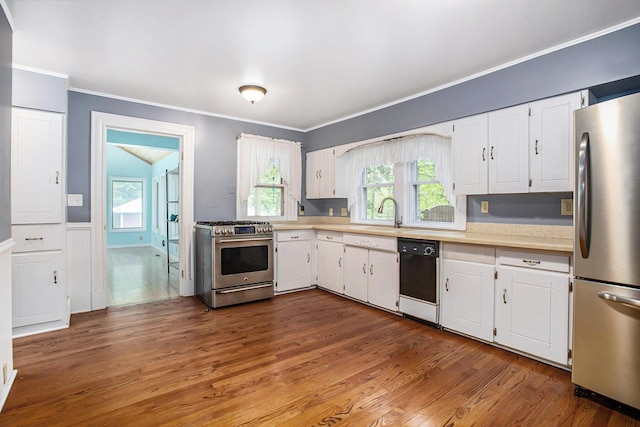 kitchen with stainless steel appliances, light countertops, white cabinets, plenty of natural light, and ornamental molding