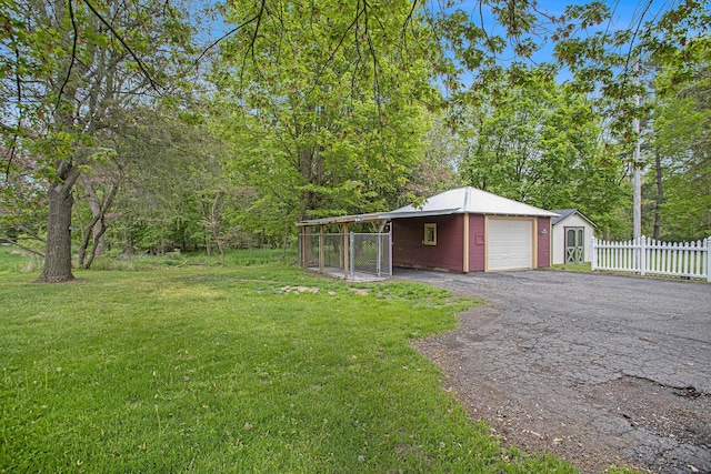 view of yard with an outdoor structure, asphalt driveway, and a detached garage