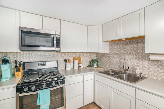 3957 Cleveland Dr W, Bitely, MI 49309 - kitchen featuring appliances with stainless steel finishes, a sink, light countertops, white cabinetry, and backsplash