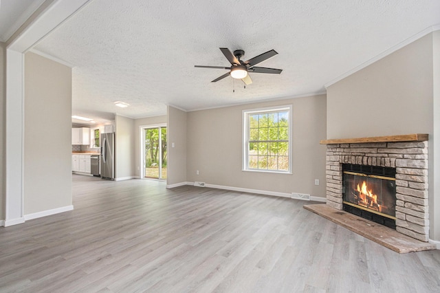 unfurnished living room featuring a fireplace, light wood finished floors, healthy amount of natural light, ceiling fan, and a textured ceiling